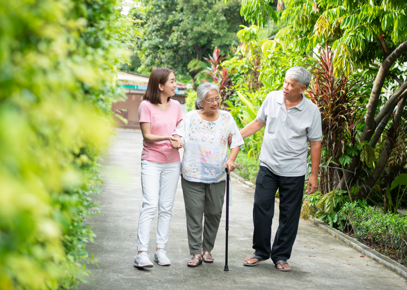 21_insight---16_9 Asian elderly woman used cane for walking. Daughter and husband help support when walking at green park. Feeling happy.